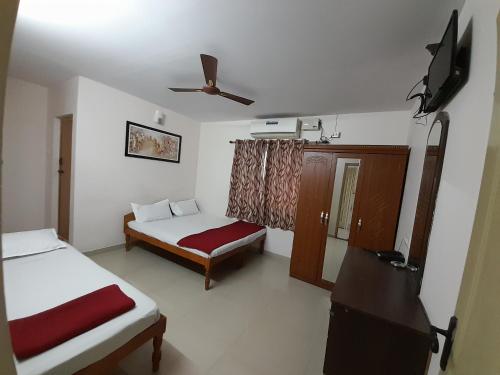 a room with two beds and a flat screen tv at SUPREME RESIDENCY in Coimbatore