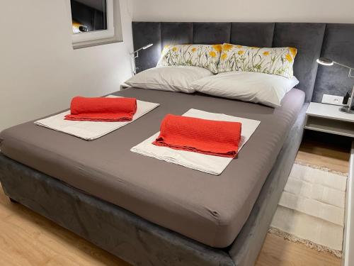 a bed with two red pillows on top of it at Artatore24 - Modern and stylish Apartments in Mali Lošinj