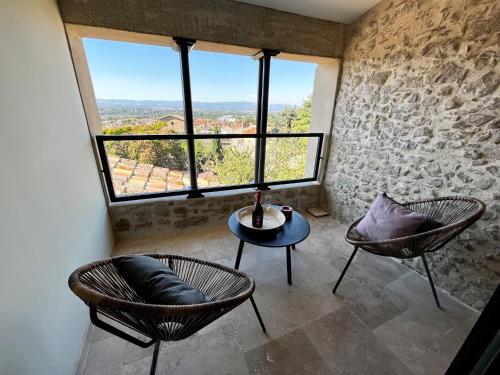 カルカソンヌにあるLe Donjon de Lily - Cœur de La Cité Médiévaleの椅子2脚、テーブル、窓が備わる客室です。
