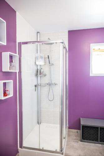 La salle de bains est pourvue d'une douche en verre aux murs violets. dans l'établissement VILLA COSYFAMILY PISCINE JACUZZI WIFI 15MIN PLAGE idéal FAMILLE - TopProsConciergerie, à Pérols