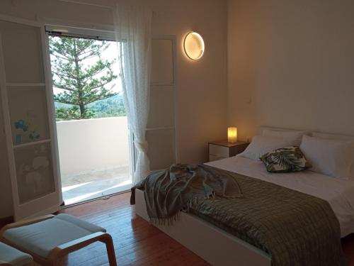 a bedroom with a bed and a window and a chair at Olive Hill House in Vragkaniótika