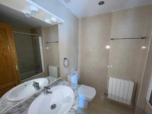 a bathroom with a sink and a toilet and a mirror at Duplex tres habitaciones Pirineo in Boltaña