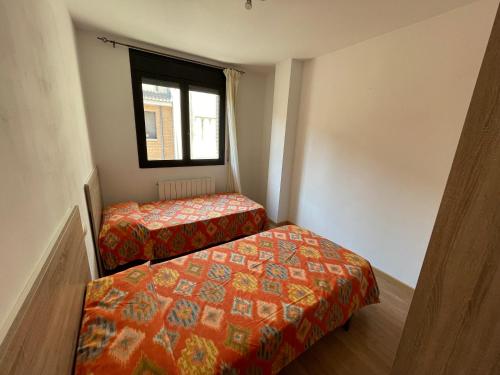 a small room with two beds and a window at Duplex tres habitaciones Pirineo in Boltaña