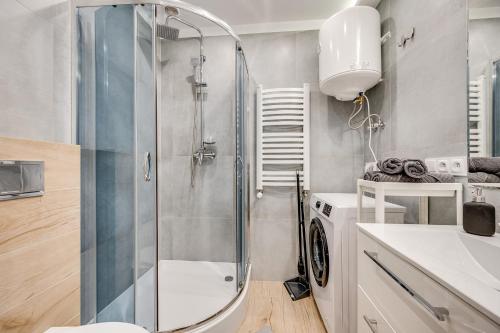 y baño con ducha, lavabo y lavadora. en Central Platinum Apartments 15, en Rybnik