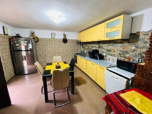 a kitchen with yellow cabinets and a table and a refrigerator at Casa Petrișor in Corbi