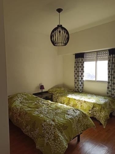 a bedroom with two beds and a chandelier at HERMOSO DEPARTAMENTO in Rosario
