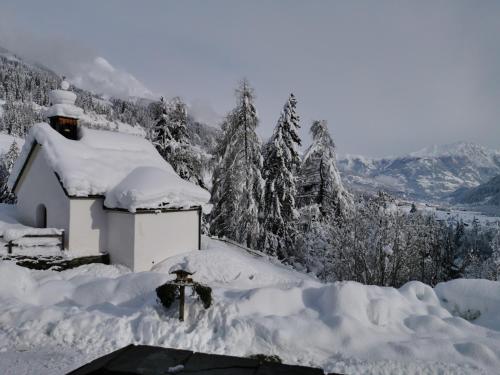 a house covered in snow with trees and mountains at Ferienwohnung Mühlburger in Virgen