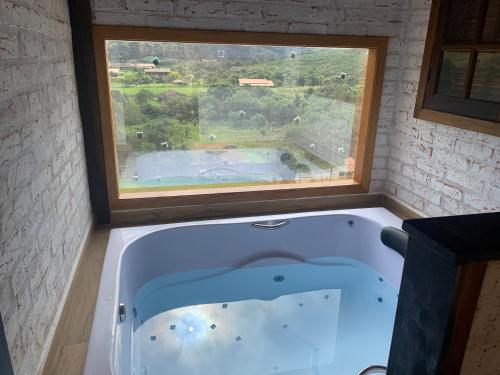 eine große Badewanne in einem Zimmer mit Fenster in der Unterkunft chalés Roma in Santo Antônio do Pinhal