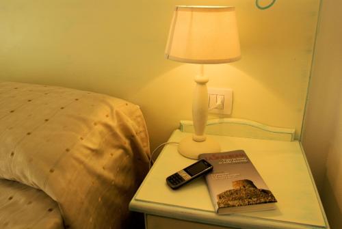 a lamp and a book on a table next to a bed at Sa Fiorida Appartamenti in Valledoria
