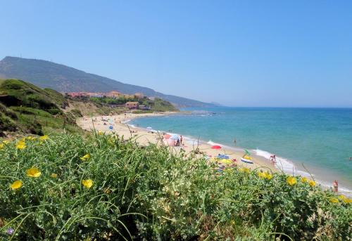 a beach with people and umbrellas and the ocean at Sa Fiorida Appartamenti in Valledoria