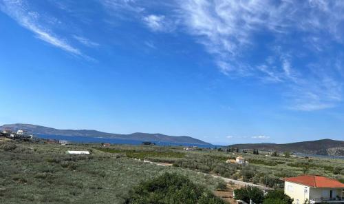a view of a field with mountains and a blue sky at Holiday House Ermionida in Thermisia