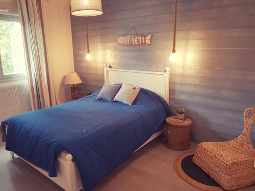 een slaapkamer met een blauw bed en een stoel bij Maison SPA proche gare et centre ville in Le Teich