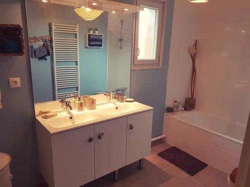 La salle de bains est pourvue d'un lavabo, d'un miroir et d'une baignoire. dans l'établissement Maison SPA proche gare et centre ville, au Teich
