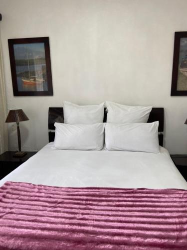 Unit 3, Marine Terrace في مارغيت: غرفة نوم مع سرير أبيض كبير مع بطانية أرجوانية