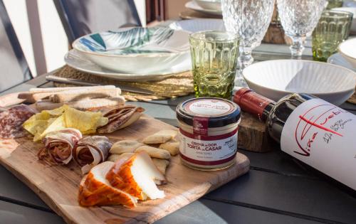 a table with a cutting board with cheese and a bottle of wine at Luz del Tajo in Alcántara