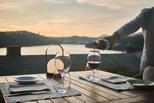 a person pouring wine into two wine glasses on a table at Octant Douro in Castelo de Paiva