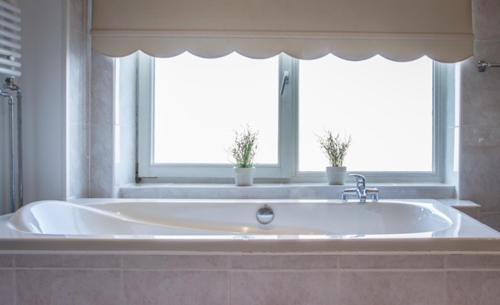 a large bath tub in a bathroom with two windows at Florian Studio's in Zandvoort