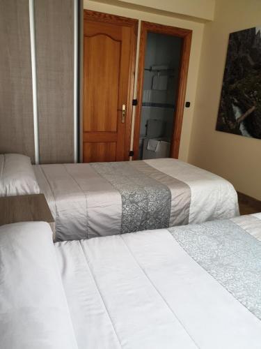 a bedroom with two beds and a bathroom with a door at Hotel Naranjo De Bulnes in Arenas de Cabrales