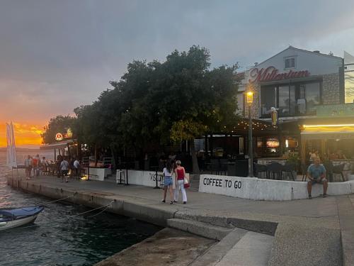 a group of people walking on a sidewalk next to the water at Hotel Millenium deluxe in Selce