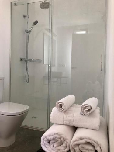 a bathroom with a shower and a toilet and towels at Cabañas Rias Baixas in Pobra do Caramiñal