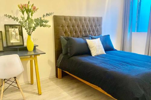 a bedroom with a blue bed and a table with a vase at Amazing Cozy Apartment in Condesa in Mexico City