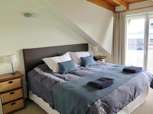 Schlafzimmer mit einem Bett mit blauer Bettwäsche und einem Fenster in der Unterkunft Bariloche Lake View Apartments in San Carlos de Bariloche