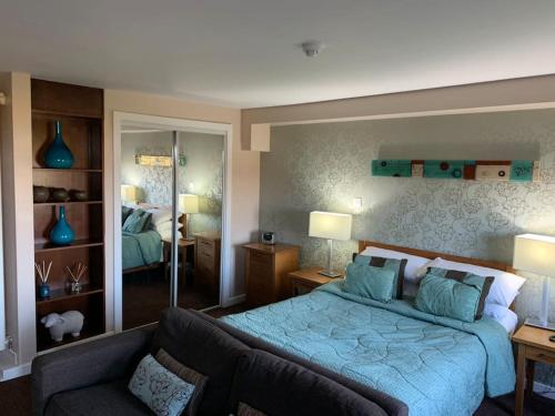 a bedroom with a blue bed and a couch at Ullswater Suite in Penrith