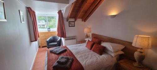 um quarto com uma cama, uma cadeira e uma janela em The Crumplehorn Inn & Mill em Polperro