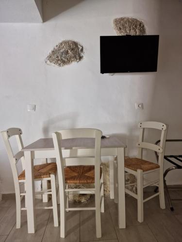 a white table and chairs with a tv on a wall at John Akroyiali in Loutro