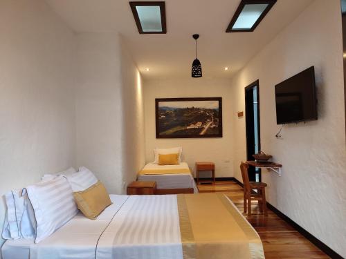 a hotel room with two beds and a flat screen tv at Hotel Boutique La Leyenda 1860 in Salamina