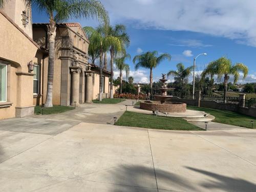 a park with a fountain and palm trees and a building at LuxHome Suites & Villa in Riverside