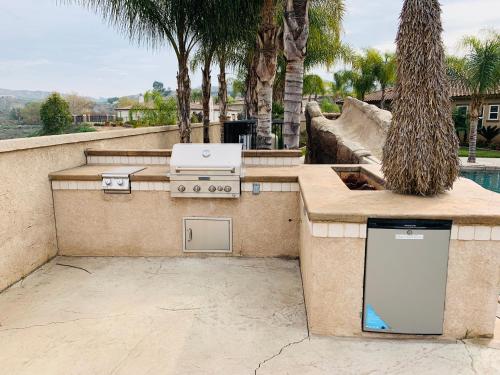 a barbecue grill in a patio with palm trees at LuxHome Suites in Mansion in Riverside