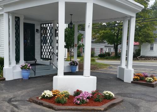 a porch with pots of flowers on a house at Windrifter Resort in Wolfeboro