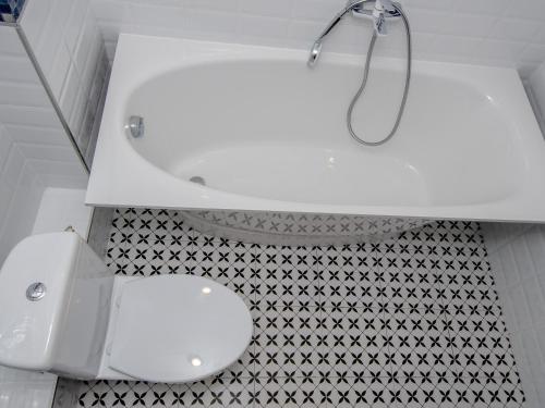 a white bathroom with a toilet and a sink at Jūras 4 Apartament in Ventspils