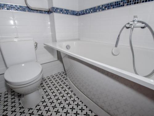 a white bathroom with a toilet and a bath tub at Jūras 4 Apartament in Ventspils