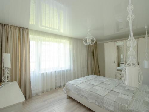 a white bedroom with a bed and a large window at Jūras 4 Apartament in Ventspils