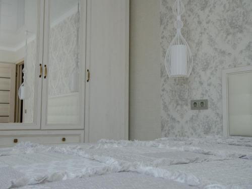 a white bedroom with a bed and a mirror at Jūras 4 Apartament in Ventspils