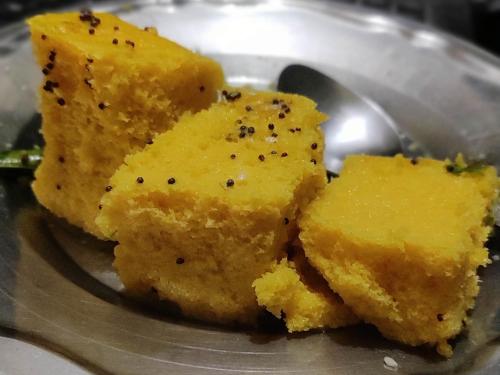 four pieces of food on a plate with a spoon at Ira Homestay Mathura - Divine Spiritual Stay in Mathura
