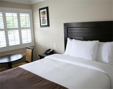 a bedroom with a bed and a table and a window at Raincross Hotel Riverside in Riverside