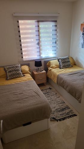 a bedroom with two beds and a window with blinds at Geweldig Appartement in Los Alcázares direct aan de Boulevard in Los Alcázares