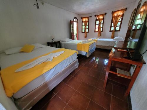 a bedroom with two beds and a table and windows at Hotel y Restaurante La Cabaña el Viajero in Castillo de San Felipe