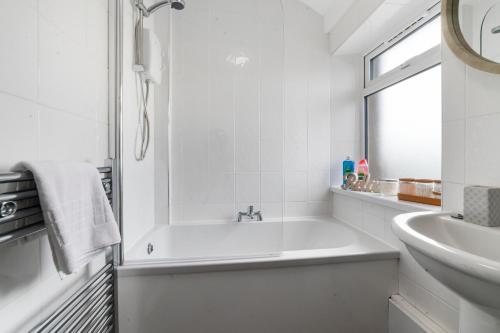 a white bathroom with a tub and a sink at Village Cwtch Whitchurch 2 Bedroom Apartment in Cardiff