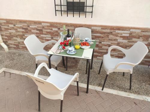 a table with white chairs and a plate of fruit at Casita La Playa in Málaga