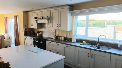 a kitchen with white cabinets and a large window at Causeway Coast Ground Floor Apartment Sleeps 5 in Armoy