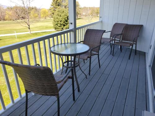 three chairs and a table on a porch with a view at Windrifter Resort in Wolfeboro
