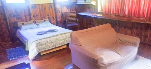um quarto com uma cama e uma cadeira em Chalé do Coiote em Maromba em Visconde de Mauá
