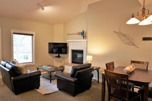 a living room with a fireplace and a table and chairs at Lakefront Gull Lake 2BR Condo Boat Rentals Available Bay Colony 773 in Nisswa