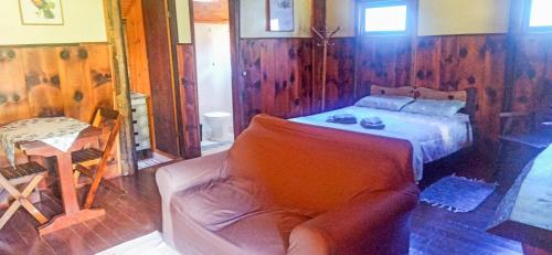 um quarto com uma cama e um sofá em Chalé do Coiote em Maromba em Visconde de Mauá