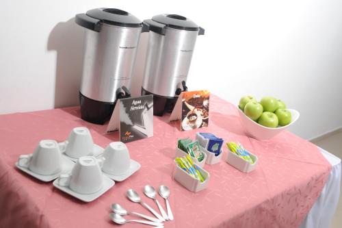 a table with a pink table cloth with cups and spoons at Hotel San José Plaza in Bucaramanga