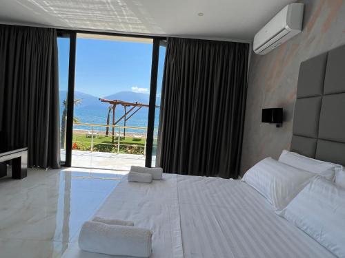a bedroom with a large white bed with a view of the ocean at Hotel Victoria in Pogradec
